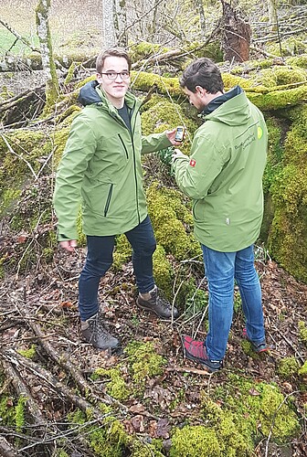 Ranger Florian Schmidt und FÖJler Tom Killius im Wald Zwei junge Männer stehen im Wald mit einem Smartphone