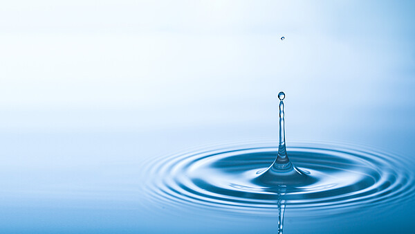 Ein Tropfen Wasser fällt in ein volles Becken Wasser