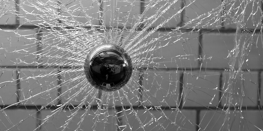 Durchwurf einer Scheibe Eine Glasscheibe vor einer Mauer wird mit einer Kugel beworefn und zersplittert